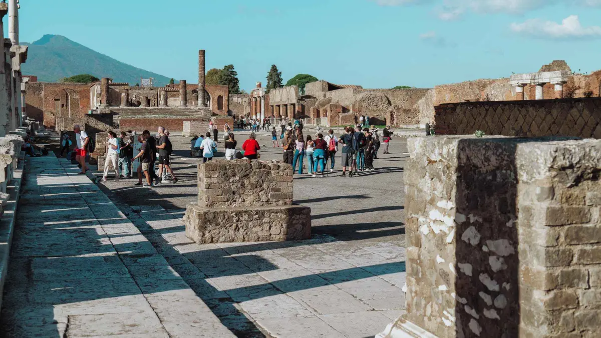 A small group on the gravel path below the Mount Vesuvius crater rim with the bay behind, the climb on the Pompeii and Mount Vesuvius tour with transfers from Sorrento, Campania, Italy